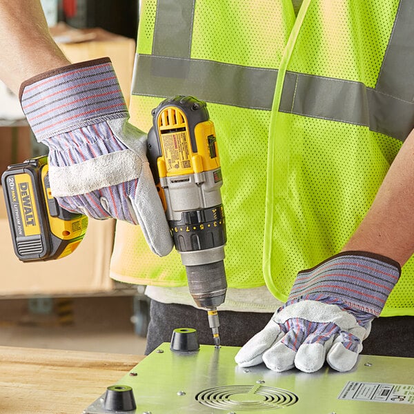A gloved hand using a yellow drill.