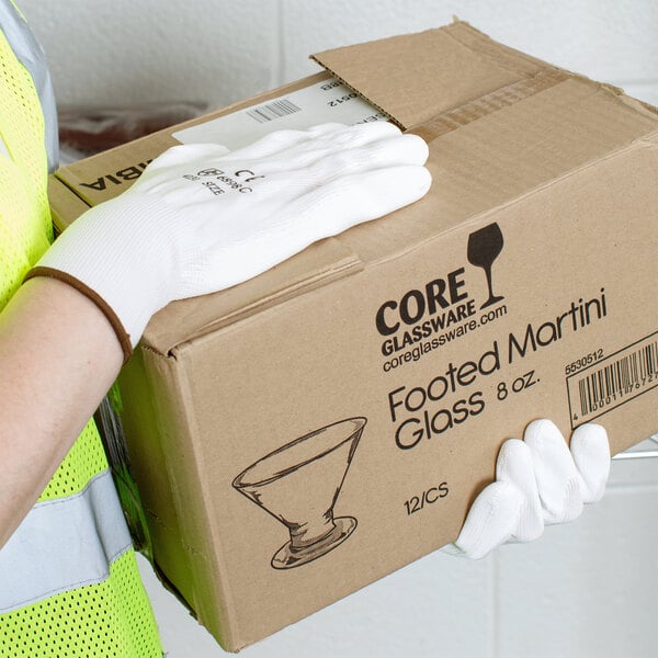 A person wearing Cordova white gloves with white polyurethane palm coating holding a box.