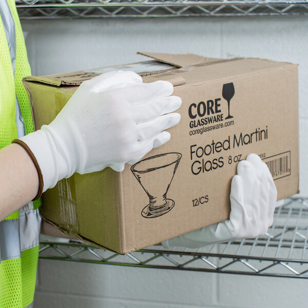 A person wearing Cordova white nylon gloves holding a box.