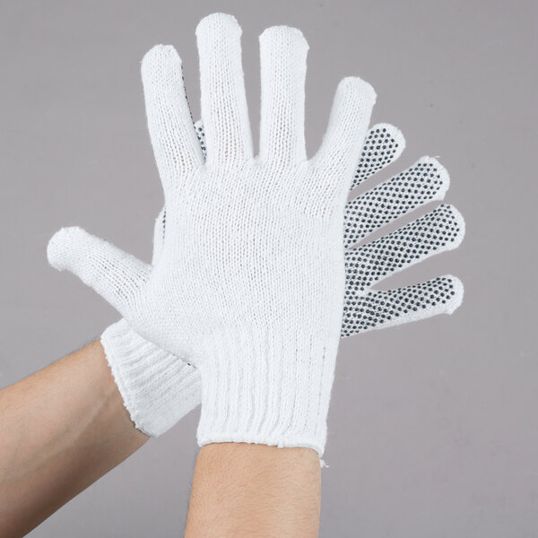 A pair of hands wearing Cordova white work gloves with black dots on the palms.