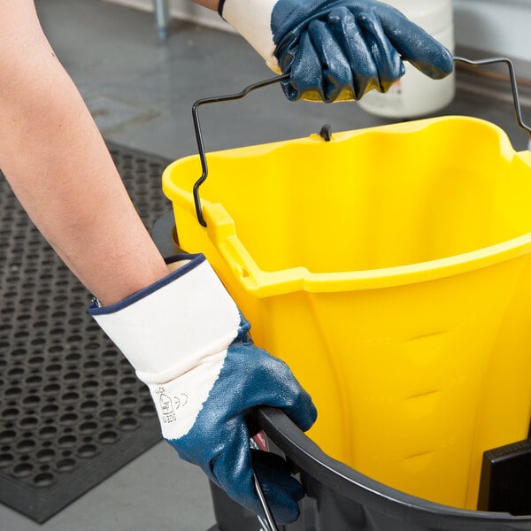 A person wearing Cordova supported palm coated gloves with a yellow bucket.