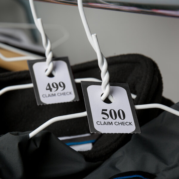 A pair of clothes with Choice Black 3 Part Paper Coat Room Check Tickets hanging on them.