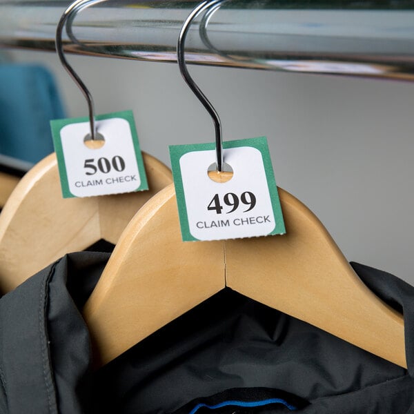 A rack of clothes with Choice Green paper coat check tickets on them.