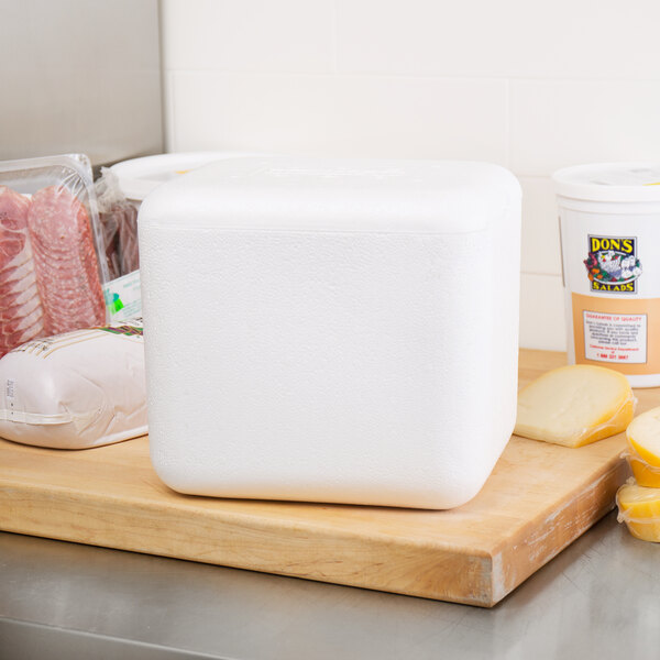 A Nordic insulated white polystyrene cooler on a table with food inside.
