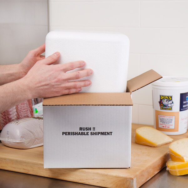 A person's hands opening a white Nordic insulated shipping box with a label on a white surface.