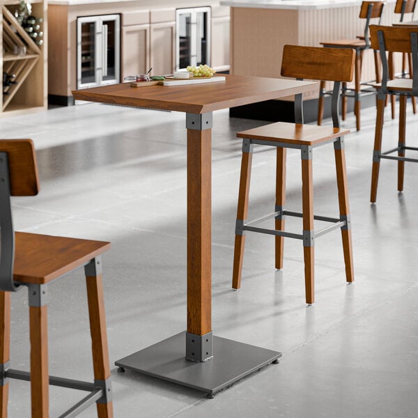 A Lancaster Table & Seating live edge wood bar table with stools in a restaurant.