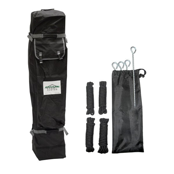 A black carrying bag, four bundles of black rope, four metal stakes, and a black drawstring pouch are displayed against a white background.