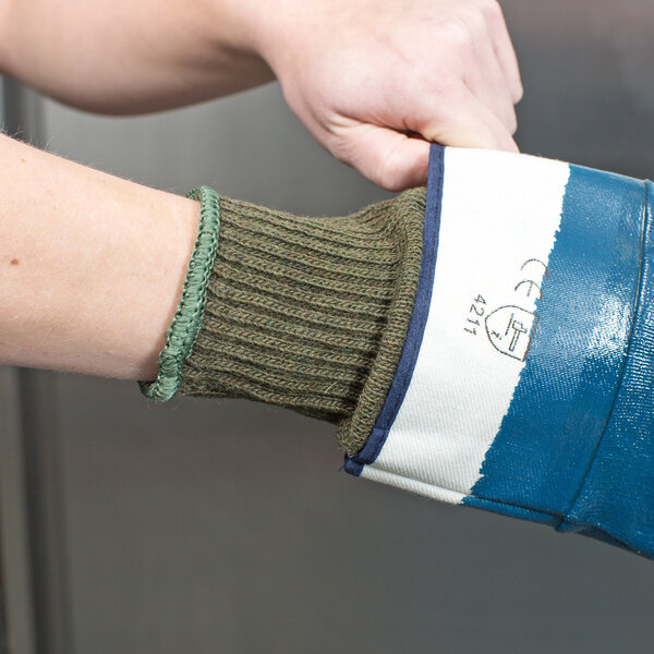A person's hand wearing a green and white Cordova work glove.