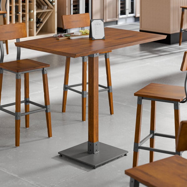A Lancaster Table & Seating wooden bar height table with a live edge and rustic walnut finish and metal legs.