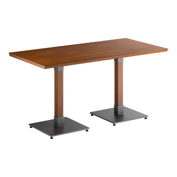 A rectangular table with a solid wood top in a walnut finish and two square metal pedestal bases.