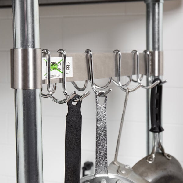 A Regency stainless steel leg mounted pot rack with hooks holding utensils.