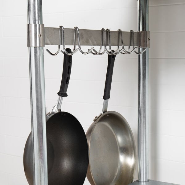 A Regency stainless steel leg mounted pot rack with pans hanging from it.