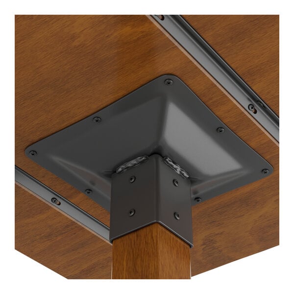 A close-up view of the underside of a wooden table with a metal mounting bracket securing the leg.