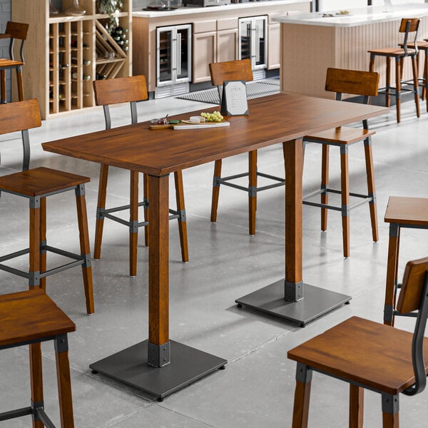 A Lancaster Table & Seating live edge bar height table with a rustic walnut finish and wooden stools.