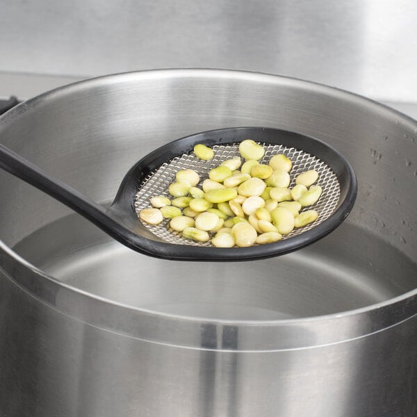 A person using a Matfer Bourgeat fine mesh skimmer to spoon food out of a pot.