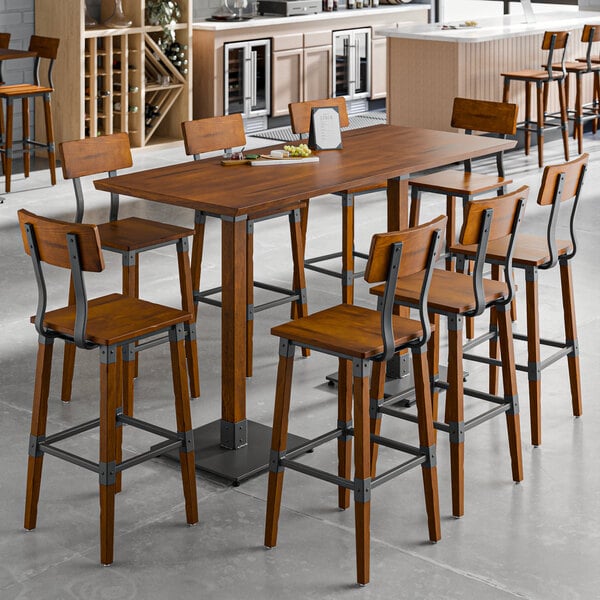 A Lancaster Table & Seating rustic walnut live edge bar height table with chairs around it.