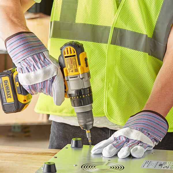 A man in Cordova striped canvas and leather work gloves using a drill.