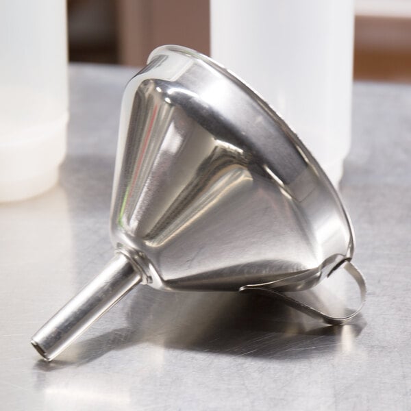 A Matfer Bourgeat stainless steel funnel with a detachable strainer on a table.