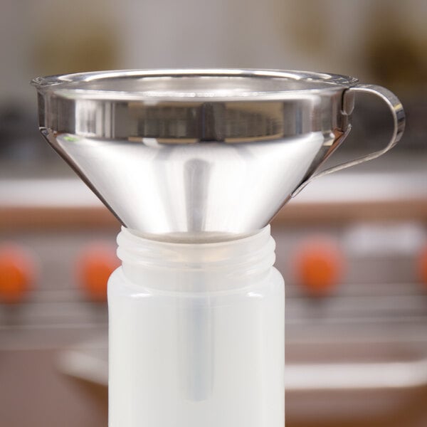 A close-up of a Matfer Bourgeat stainless steel funnel with a detachable strainer.