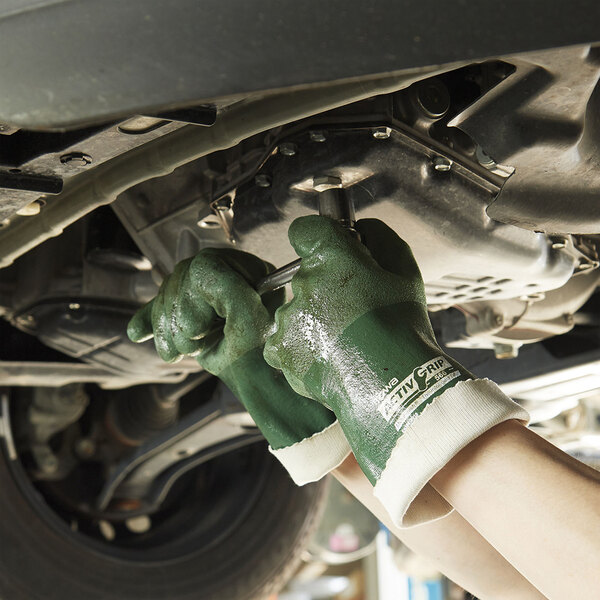A pair of green Cordova ActivGrip nitrile gloves with polyester/cotton lining being worn while working on a car.