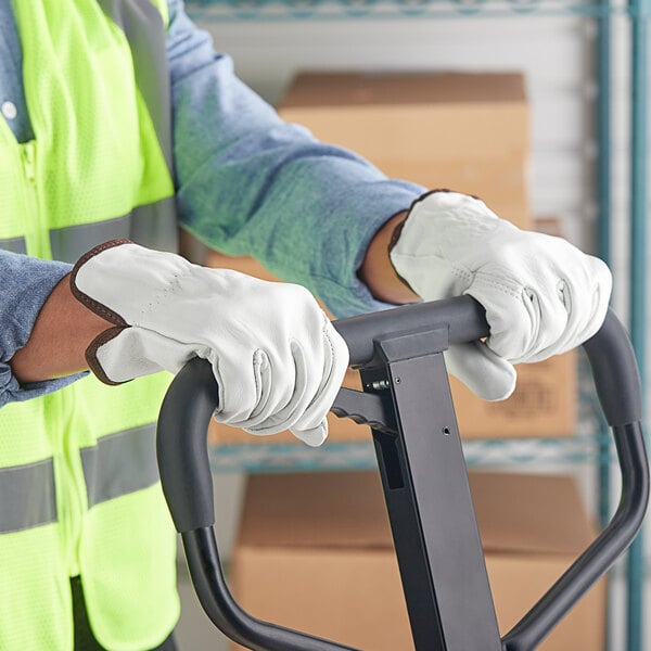 A person wearing Cordova Standard Grain Cowhide Leather Driver's Gloves holding a hand truck handle.