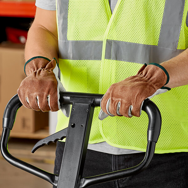 A person wearing Cordova Select grain cowhide leather driver's gloves holding a hand truck.