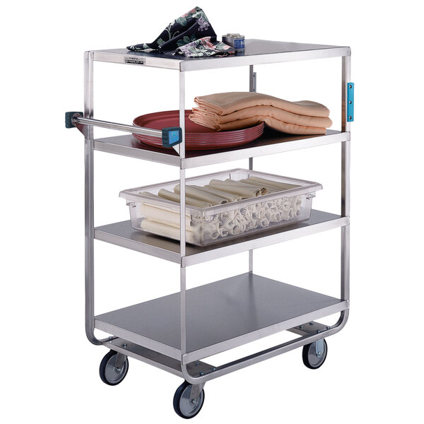 A Lakeside stainless steel utility cart with three shelves holding towels and food.