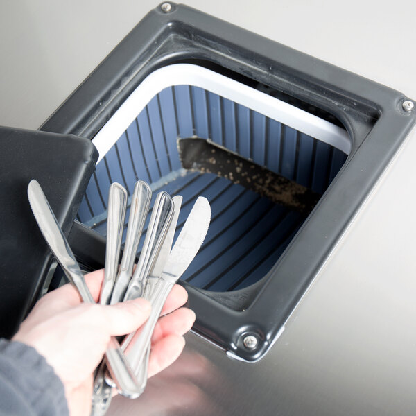 A hand holding a knife and fork in a metal box.