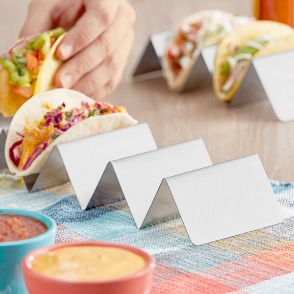 A person holding a Choice stainless steel taco holder with tacos.