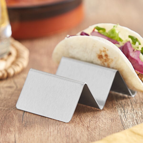 A stainless steel mini taco holder with a taco in each compartment.