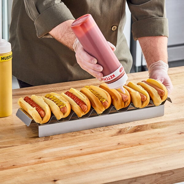 Chef squeezing ketchup onto hot dog in a compartment hot dog tray