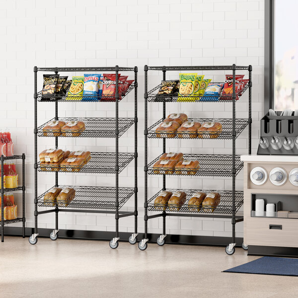 A bakery store with a Regency black angled mobile merchandising rack holding bread and snacks.