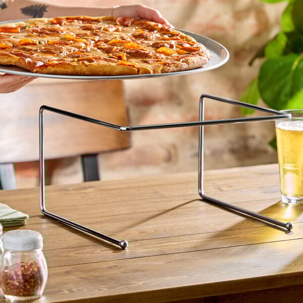 A chrome metal pizza stand designed to hold a pizza tray above a table surface.
