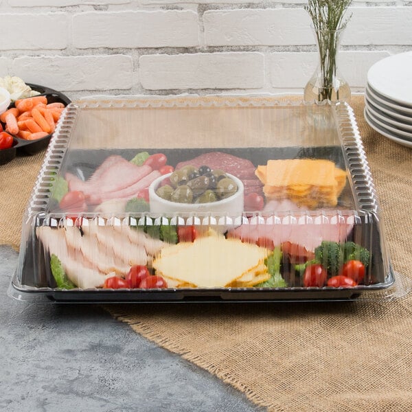 A black Fineline plastic square catering tray with meat, cheese and vegetables on a table.