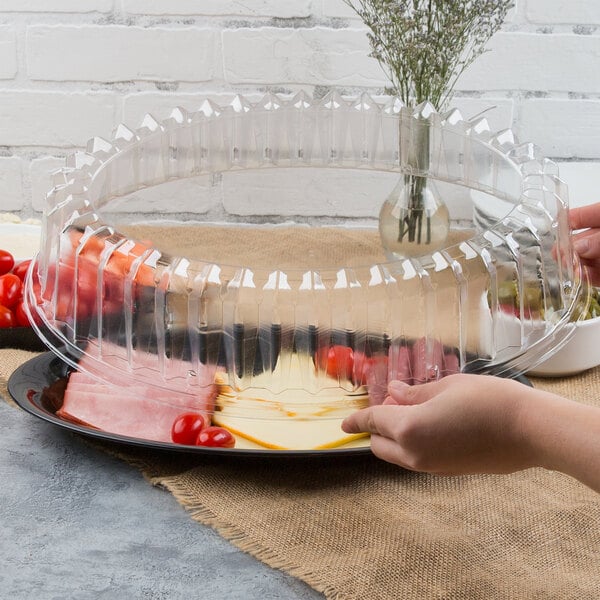 A person placing a plastic oval dome lid on a plastic tray.