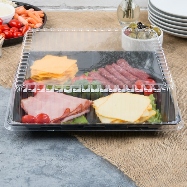 A Fineline clear plastic lid on a tray of vegetables and dip.