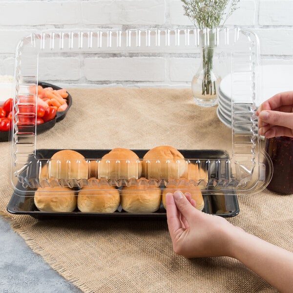 A hand holding a Fineline clear plastic rectangular container with food in it.