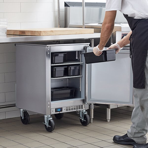 A man in a kitchen using a Beverage-Air undercounter freezer.