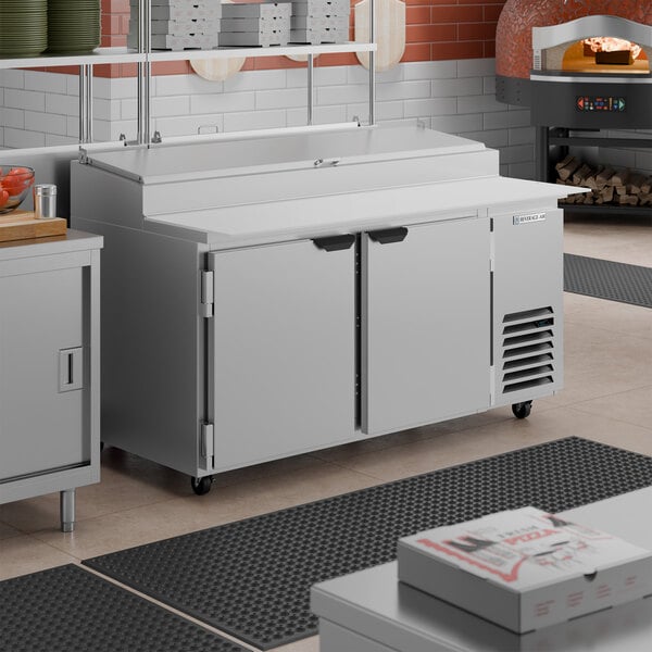 A stainless steel two-door refrigerated pizza prep table with a raised ingredient rail and work surface.