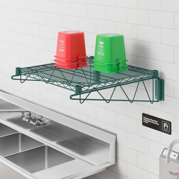 A Regency green wire wall mount shelf holding green cups.