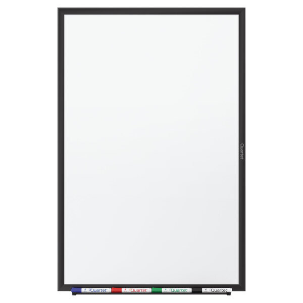 A Quartet melamine whiteboard with a black aluminum frame with markers on it.
