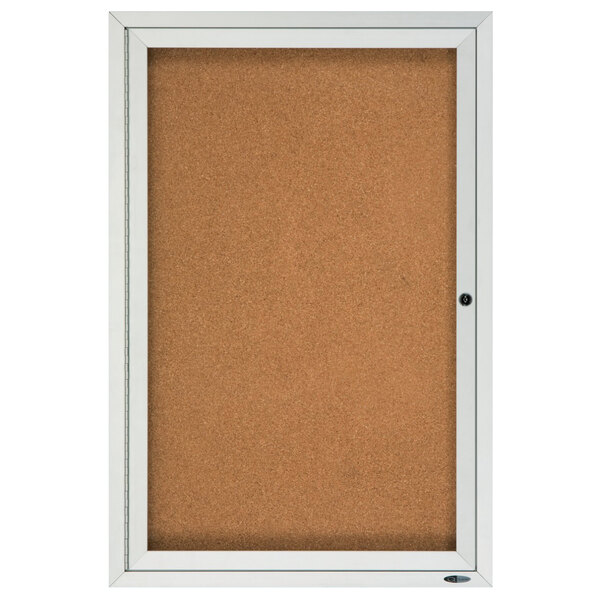 A white framed Quartet cork board cabinet with 1 door.