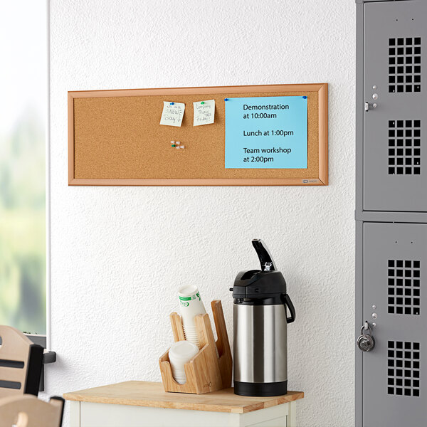 A Quartet cork board with an oak frame on a wall.