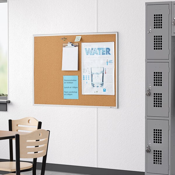 A Quartet cork board with papers on it hanging on a white wall.