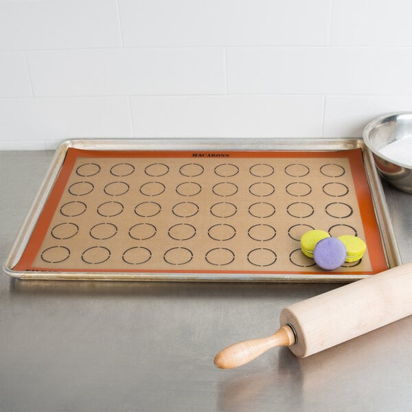 A Sasa Demarle SILPAT baking mat with macaron circles and a rolling pin on it.