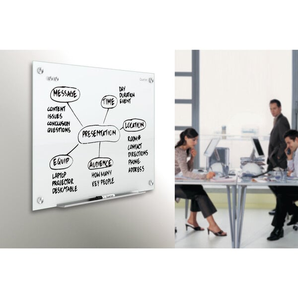 A woman using a Quartet white glass markerboard to write on.