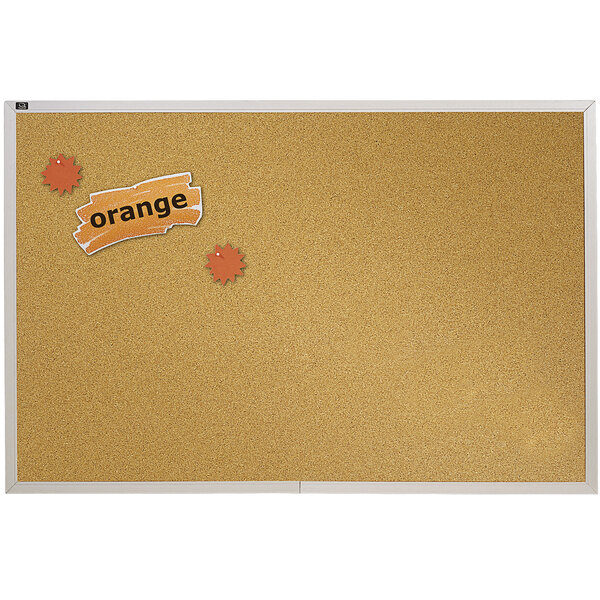 A Quartet cork board with orange stickers on it.