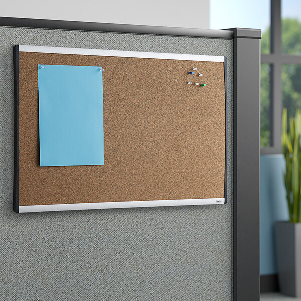 A cork board with a blue paper pinned to it.