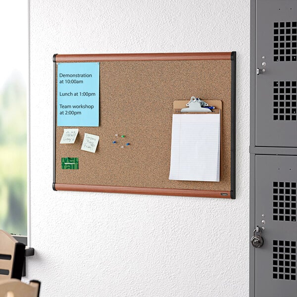 A Quartet cork board with a cherry plastic frame.