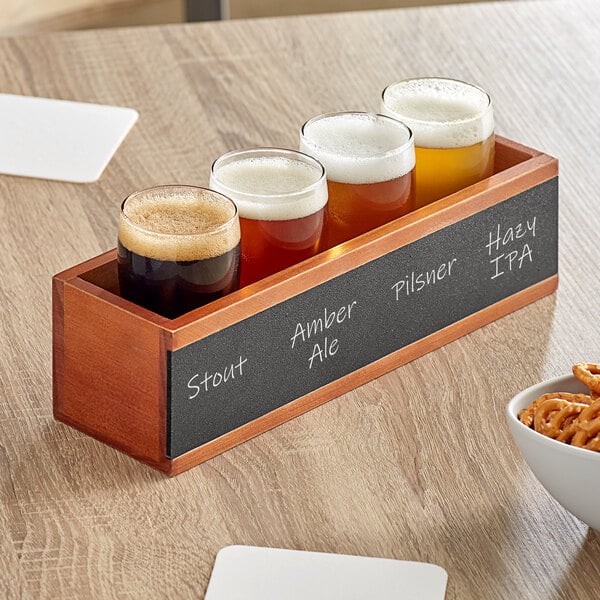 An Acopa wooden flight crate with pub tasting glasses of beer and a bowl of pretzels on a table.